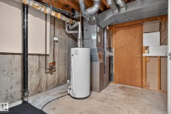 Utility area featuring a water heater, furnace system, exposed ceiling joists, and concrete flooring - 