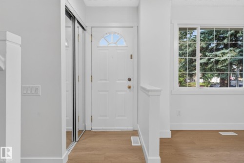 Entryway featuring wood-finish flooring, a white paneled door with an arched transom, and a mirrored sliding closet door - 8059 178 Street Nw, Edmonton, AB - Indoor Photo Showing Other Room