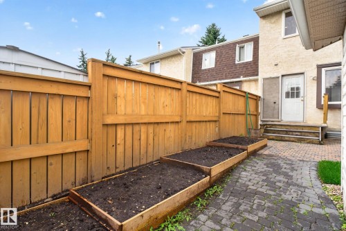 Private backyard featuring a paver patio, wood privacy fence, and multiple raised garden beds - 8059 178 Street Nw, Edmonton, AB - Outdoor With Exterior