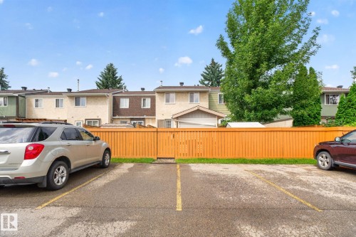 Paved parking area with marked spaces, bordered by a wooden privacy fence - 8059 178 Street Nw, Edmonton, AB - Outdoor