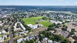 Aerial perspective showcasing a residential area with extensive green spaces, a large institutional building, and established infrastructure - 