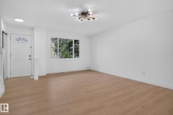 Spacious interior featuring wood-finish flooring, white walls, and a contemporary ceiling light fixture - 