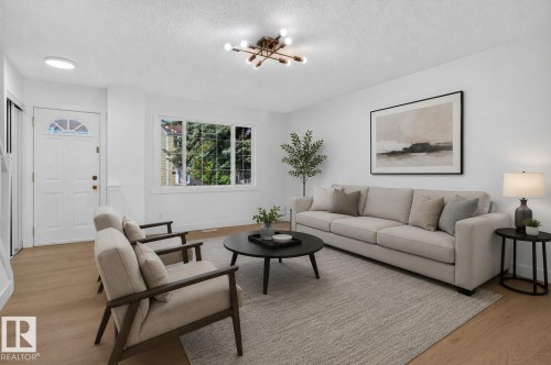 Bright living area featuring wood-finish flooring, a contemporary chandelier, white walls, and a large multi-pane window - 8059 178 Street Nw, Edmonton, AB - Indoor Photo Showing Living Room