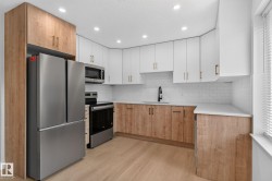 Modern kitchen featuring a stainless steel French door refrigerator, white subway tile backsplash, and two-tone cabinetry with wood-finish base cabinets and white upper cabinets - 