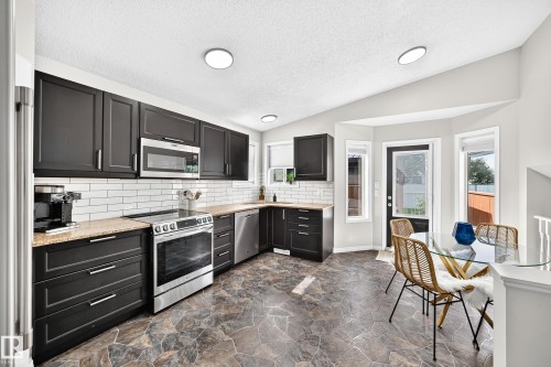 Modern kitchen featuring black cabinetry, light-toned countertops, and a white subway tile backsplash - 3729 131A Avenue Nw, Edmonton, AB - Indoor Photo Showing Kitchen With Upgraded Kitchen