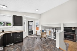 Kitchen and dining area featuring dark cabinetry, light granite-finish countertops, subway tile backsplash, and irregular-cut stone-finish flooring - 
