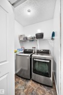 Dedicated laundry area with stone-look flooring, white walls, and a convenient wire shelf system - 