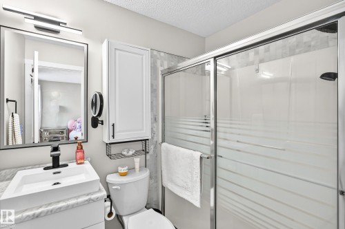 Three-piece bathroom featuring a shower with sliding glass doors and striped privacy film, a vanity with a rectangular vessel sink, and a wall-mounted medicine cabinet with integrated shelving - 3729 131A Avenue Nw, Edmonton, AB - Indoor Photo Showing Bathroom