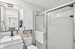 Three-piece bathroom featuring a shower with sliding glass doors and striped privacy film, a vanity with a rectangular vessel sink, and a wall-mounted medicine cabinet with integrated shelving - 