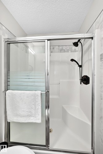 Modern shower enclosure with sliding glass doors, a built-in bench, and black-finish fixtures - 3729 131A Avenue Nw, Edmonton, AB - Indoor Photo Showing Bathroom