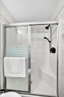 Modern shower enclosure with sliding glass doors, a built-in bench, and black-finish fixtures - 