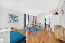 Bright dining space featuring wood-finish flooring, a modern chandelier, and light gray walls - 