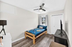 Room featuring wood-finish flooring, a double-door closet with bi-fold doors, and a ceiling fan with integrated lighting - 