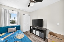 Interior room featuring wood-finish flooring, a white bi-fold closet door, and a ceiling fan with integrated lighting - 