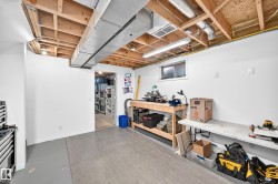Unfinished basement space with exposed wooden joists and ductwork - 