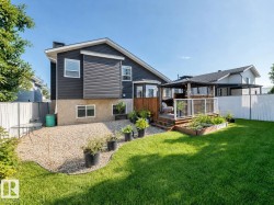 Expansive backyard featuring a manicured lawn, a raised wooden deck with white railings, and a gazebo - 