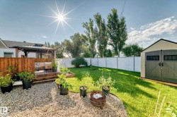 Expansive backyard with a manicured lawn, a raised wooden deck with a gazebo, a gravel patio area, a raised garden bed, and a detached storage shed - 