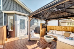 Expansive outdoor deck featuring wood-finish flooring, a built-in privacy wall, and an attached gazebo structure - 