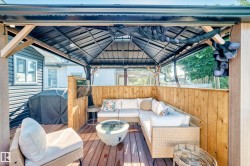 Expansive outdoor living space featuring a gazebo with a metal roof, wood deck flooring, and privacy walls - 
