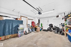 Spacious garage featuring a concrete floor, bright overhead lighting, and white walls - 