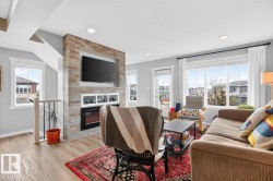 Open Concept Living Room Space featuring Large South Facing Window, Access to Balcony, Electric Fireplace, and Ample Space for Gatherings. - 