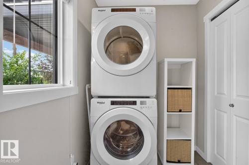 Main Floor Laundry Room featuring Stacking Washer and Dryer with Storage Space. - 1051 Cy Becker Road Nw, Edmonton, AB - Indoor Photo Showing Laundry Room