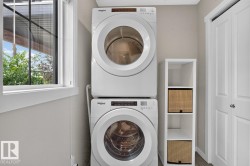 Main Floor Laundry Room featuring Stacking Washer and Dryer with Storage Space. - 