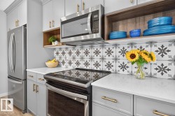 Open Concept Kitchen featuring Stainless Steel Appliances, Stylish Lighting and Accent Tiles, Bar Fridge, and Bar/Counter Seating. - 