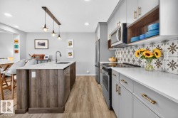 Open Concept Kitchen featuring Stainless Steel Appliances, Stylish Lighting and Accent Tiles, Bar Fridge, and Bar/Counter Seating. - 