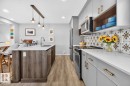 Open Concept Kitchen featuring Stainless Steel Appliances, Stylish Lighting and Accent Tiles, Bar Fridge, and Bar/Counter Seating. - 1051 Cy Becker Road Nw, Edmonton, AB  - Indoor Photo Showing Kitchen With Upgraded Kitchen 