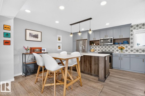 Open Concept Dining Room Space featuring Stylish Lighting, Kitchen Bar Space, and Accent Tiles. - 1051 Cy Becker Road Nw, Edmonton, AB - Indoor