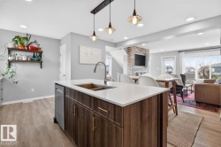 Open Concept Kitchen featuring Stainless Steel Appliances, Stylish Lighting and Accent Tiles, Bar Fridge, and Bar/Counter Seating. - 