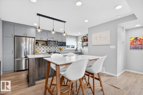 Open Concept Dining Room Space featuring Stylish Lighting, Kitchen Bar Space, and Accent Tiles. - 1051 Cy Becker Road Nw, Edmonton, AB - Indoor