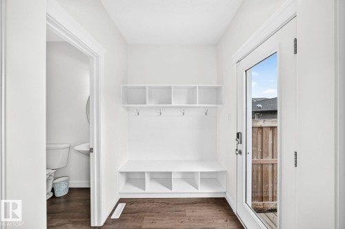 Entryway featuring built-in white cabinetry with open shelving and storage cubbies, integrated bench seating, and wall-mounted hooks - 1261 Rosenthal Boulevard Nw, Edmonton, AB - Indoor Photo Showing Other Room