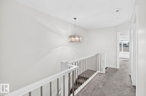 Upper-level hallway with textured ceiling, pendant light fixture, and plush gray carpeting - 1261 Rosenthal Boulevard Nw, Edmonton, AB - Indoor Photo Showing Other Room