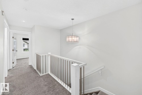 Carpeted hallway and staircase featuring contemporary metal balusters and a white handrail - 1261 Rosenthal Boulevard Nw, Edmonton, AB - Indoor Photo Showing Other Room