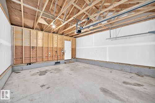Spacious garage featuring a concrete floor, exposed wooden ceiling trusses, and an automatic garage door opener - 1261 Rosenthal Boulevard Nw, Edmonton, AB - Indoor Photo Showing Garage