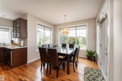 Dining area featuring abundant natural light, wood-finish flooring, a contemporary chandelier, and direct access to an exterior door - 