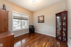 Hardwood flooring throughout featuring a large window with white trim, neutral wall paint, and a built-in overhead light fixture - 