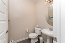 Powder room featuring a pedestal sink, round wall mirror, and vanity light fixture - 