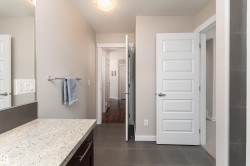 Bathroom vanity with a light speckled countertop, dark wood-finish cabinetry, and a full-width mirror - 