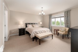 Carpeted bedroom with a large window, a multi-bulb chandelier, and warm neutral wall tones - 