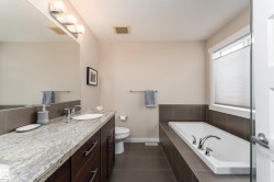 Bathroom featuring a dual-sink vanity with a light-colored countertop, dark wood-finish cabinetry, and chrome fixtures - 
