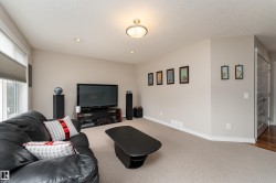 Carpeted living area featuring recessed lighting, a central flush-mount light fixture, and a window with cellular blinds - 