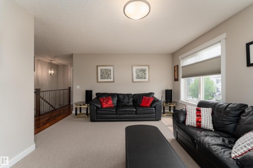 Spacious carpeted living area featuring neutral wall paint, a large window with privacy blinds, and a ceiling-mounted light fixture - 2338 Frezenberg Avenue Nw, Edmonton, AB - Indoor Photo Showing Living Room