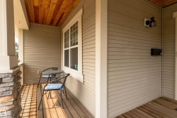 Welcoming front porch featuring horizontal siding, a wood-finish ceiling, and a stone-clad support pillar - 