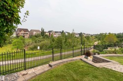 Landscaped backyard featuring paver stone patio, stone retaining walls, and a manicured lawn - 