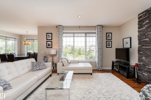 Spacious living area featuring large windows with gridded panes, recessed lighting, and rich wood-finish flooring - 2338 Frezenberg Avenue Nw, Edmonton, AB - Indoor Photo Showing Living Room