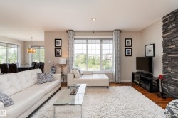 Spacious living area featuring large windows with gridded panes, recessed lighting, and rich wood-finish flooring - 