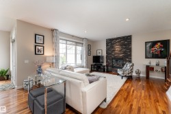 Spacious living area featuring polished wood flooring, a stone-clad fireplace, and recessed lighting - 